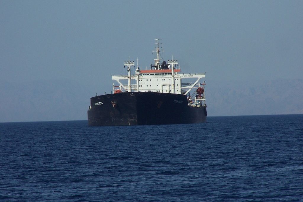 A cargo ship at anchor in calm water under a clear sky