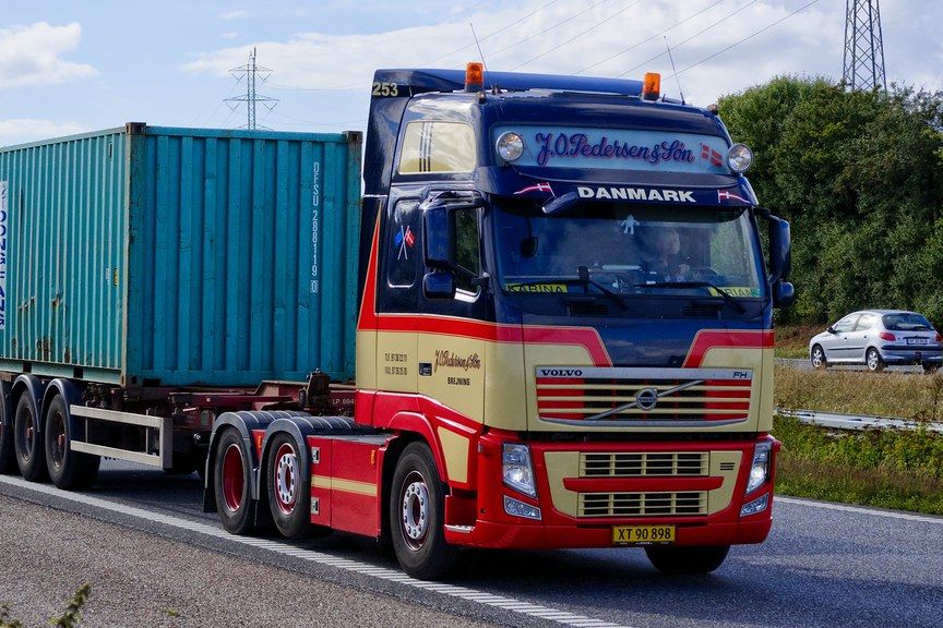 A truck hauling a teal shipping container on a motorway