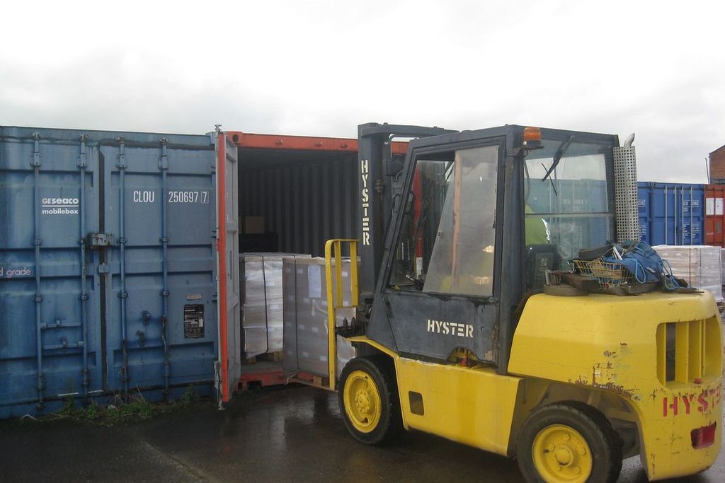 A forklift loading goods into an open shipping container