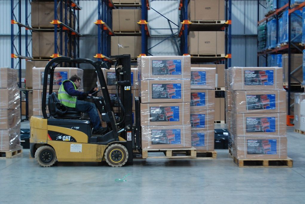 A forklift moving palletised cartons in a warehouse